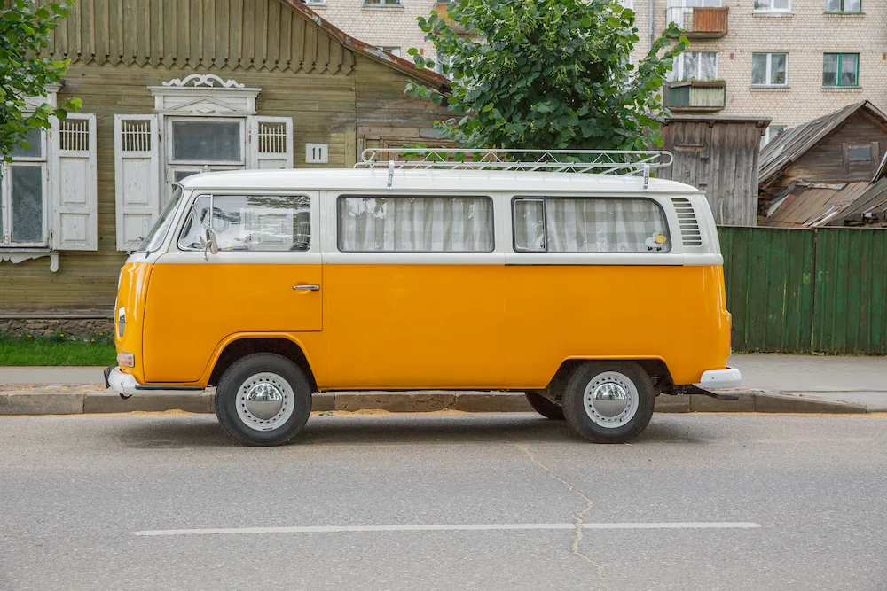 Orange and white retro VW camper van on a street.