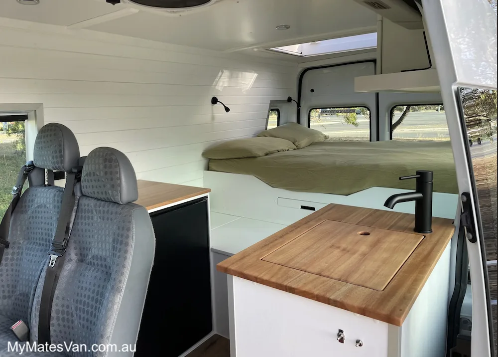 Internal view of a converted camper van showing the bed in the back.