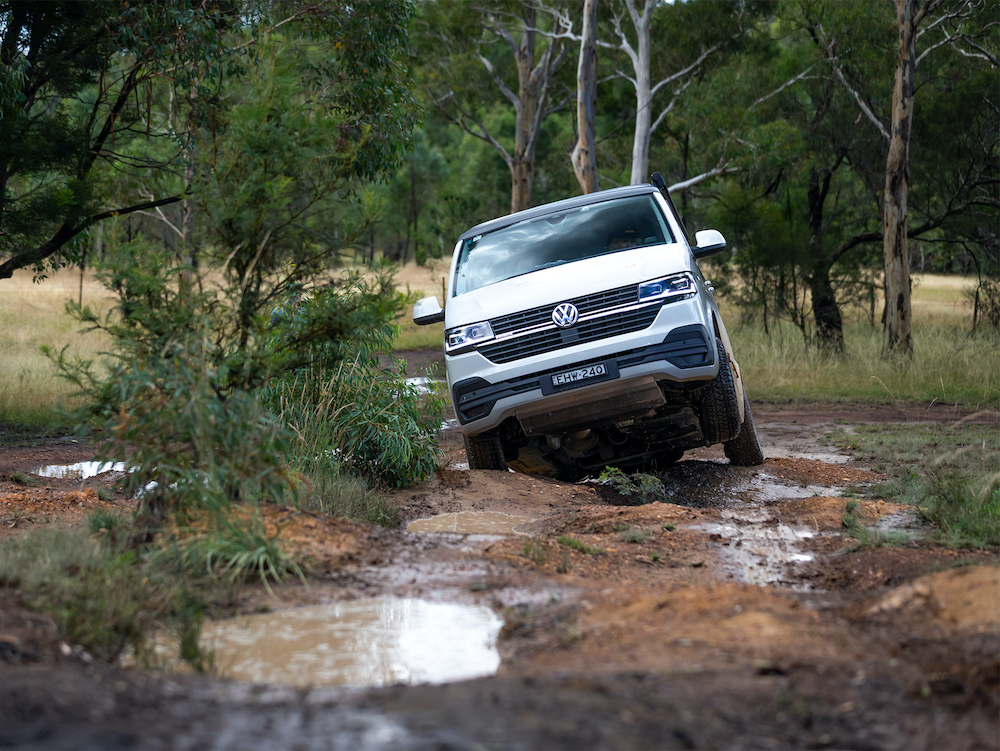 VW off road campervan driving on a muddy, uneven track in Australia