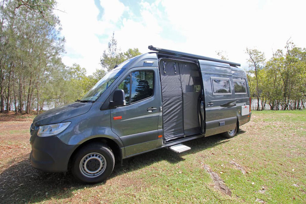 Exterior view of grey Wattle motorhome with side door open showing the fly screen across the door way.