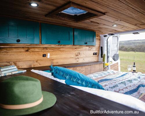 Looking across the bed in a converted van towards the open rear doors.