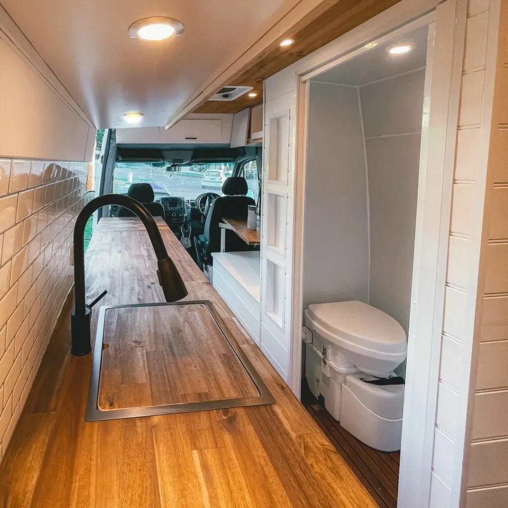 Kitchen bench inside a Sprinter camper van, also showing the composting toilet in the bathroom.