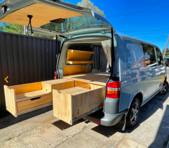 Rear door of a van open with a removable campervan kit in the back.