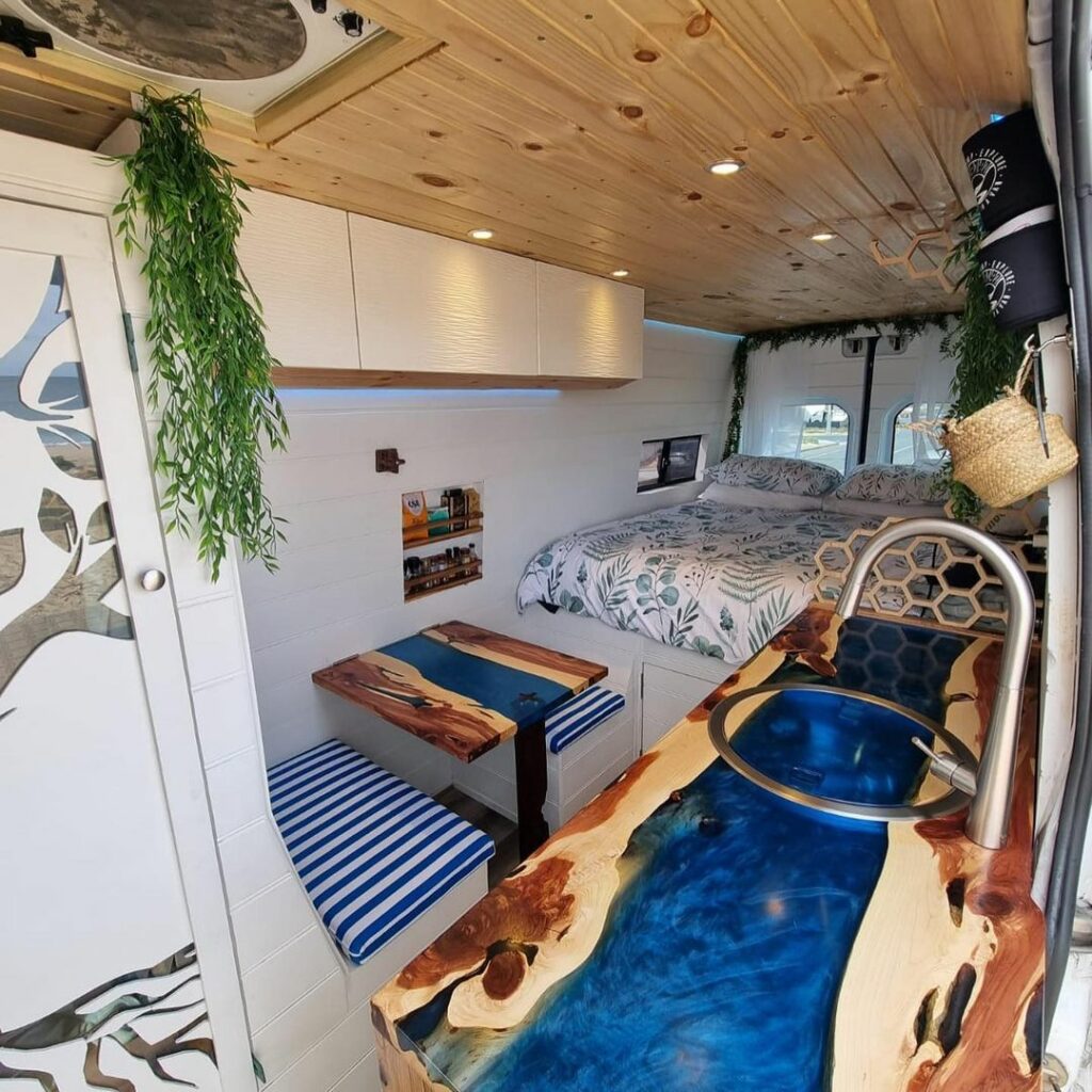 Interior of a camper van showing vibrant kitchen countertops and a bed in the back.