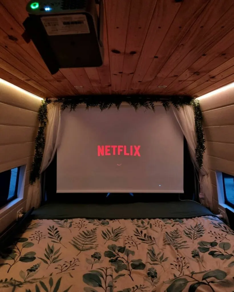 Project screen in the bed area of a cozy camper van.