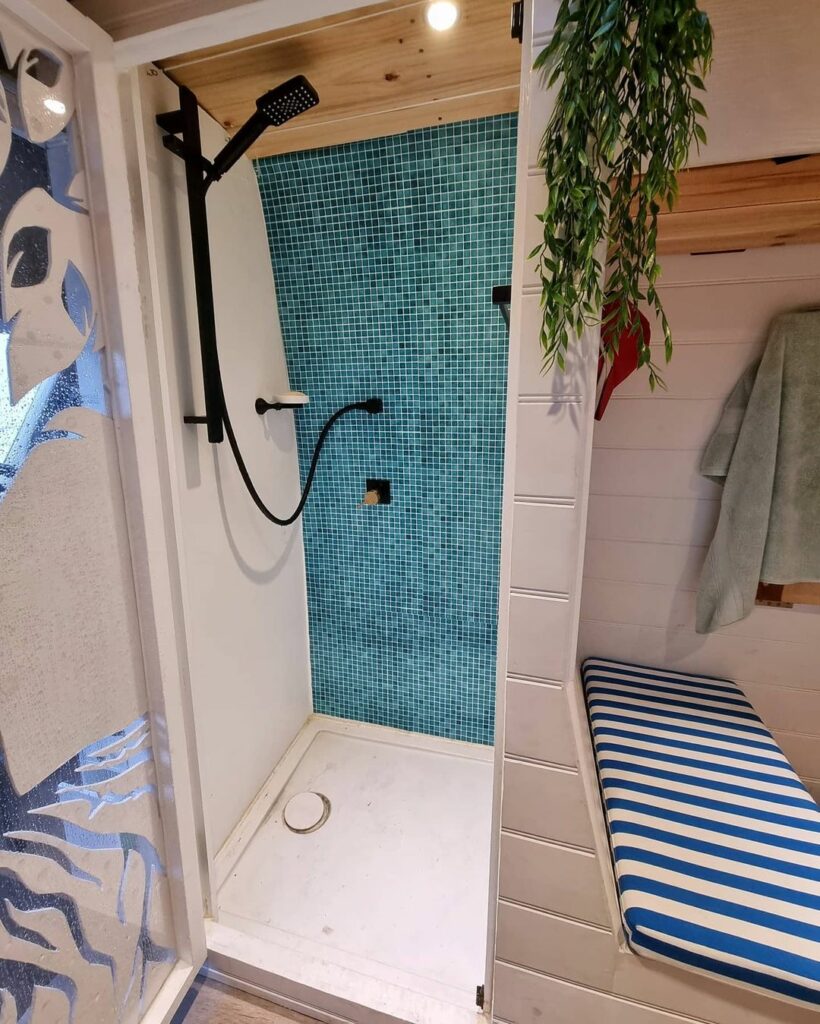 Camper van shower cubicle with aqua blue tiles on the wall.