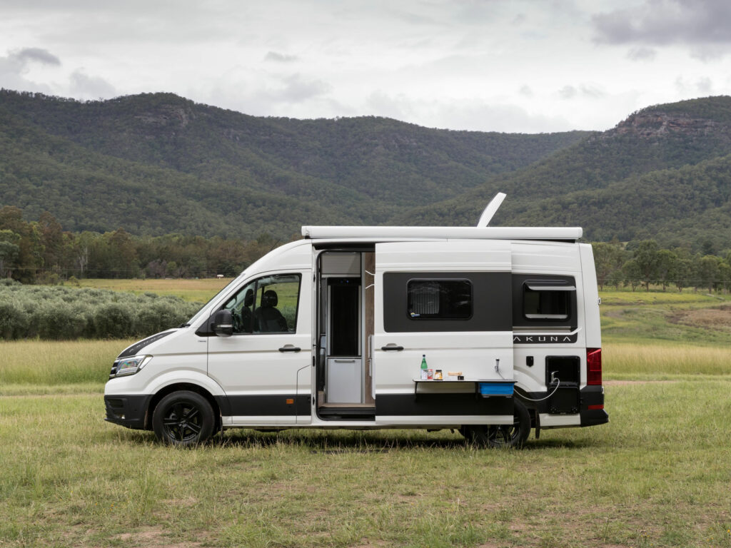 Side view of a white campervan in Australia with sliding door open.