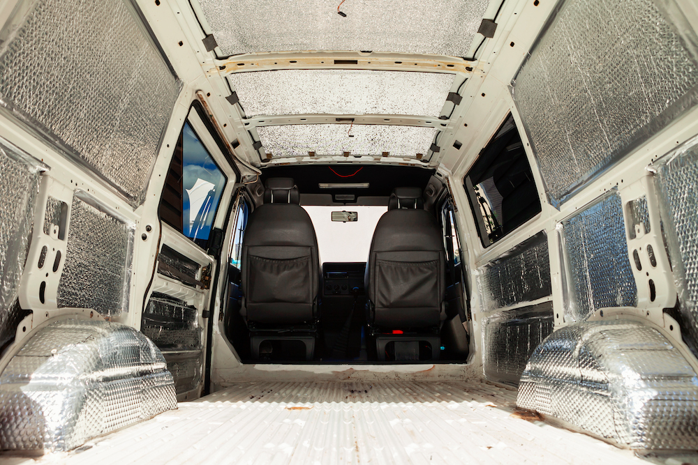 Interior of a van, being converted into a camper van, with insulation on the walls and ceiling.