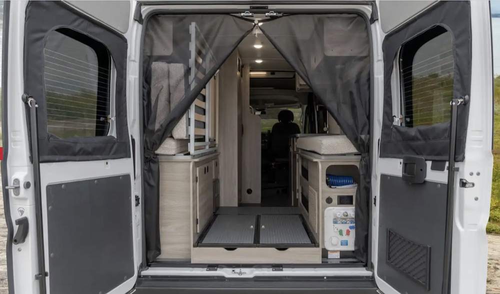 Looking into a Winnebago Solis camper van through the open rear doors.