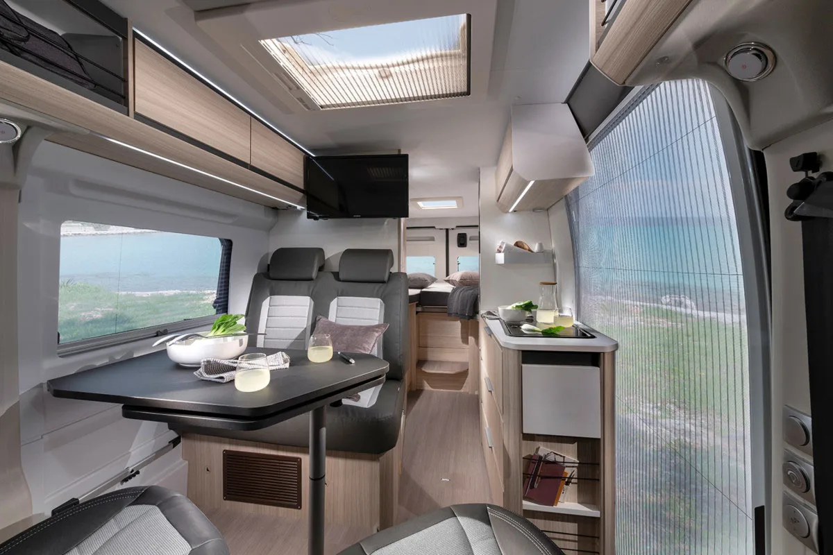 Interior of the Adria Twin campervan showing the dining area and kitchen.