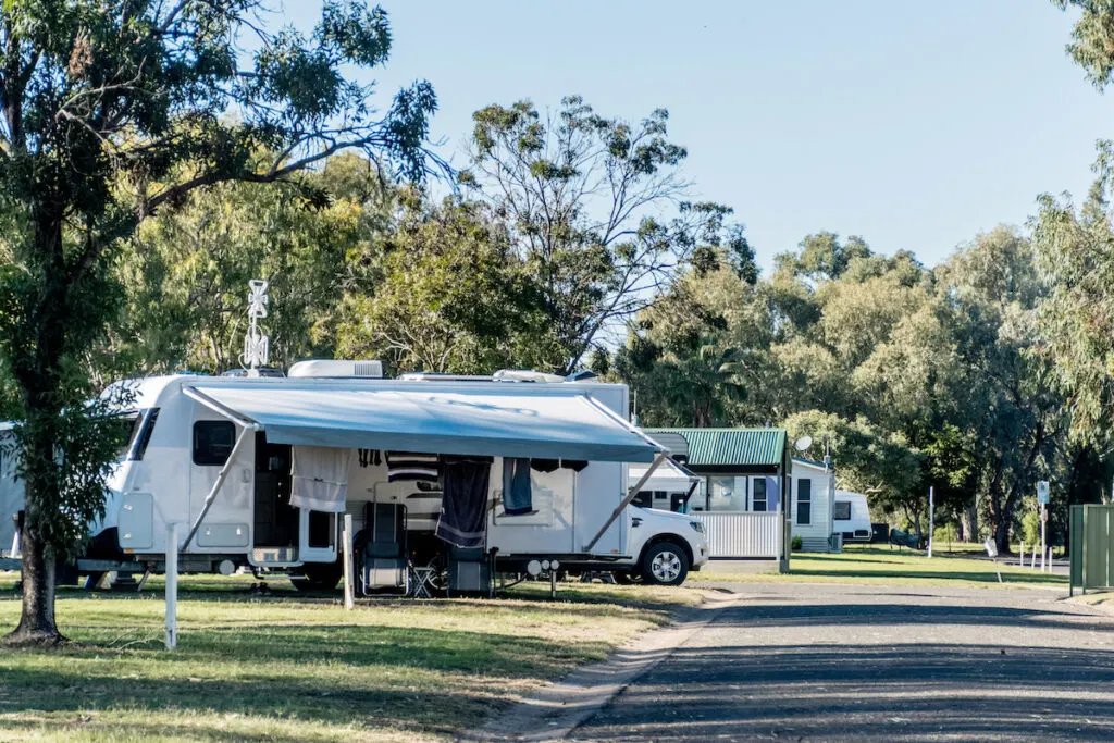 Caravan park in Australia showing a caravan with the awning open, and a motorhome behind it.