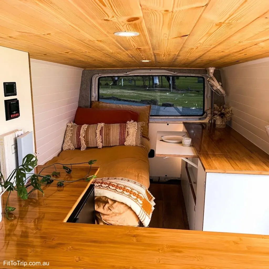 Cozy interior of a campervan with a single bed and small kitchen.
